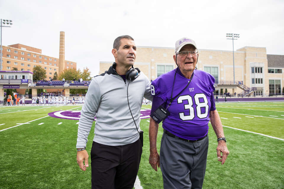 Head Coach Glenn Caruso walks with Tom Pacholl, 93, who was honored as one of the University of St. Thomas Football Team’s oldest living alumni at O’Shaughnessy Stadium on September 25, 2021 where St. Thomas won their first Division 1 home game against Butler University with a final score of 36-0.