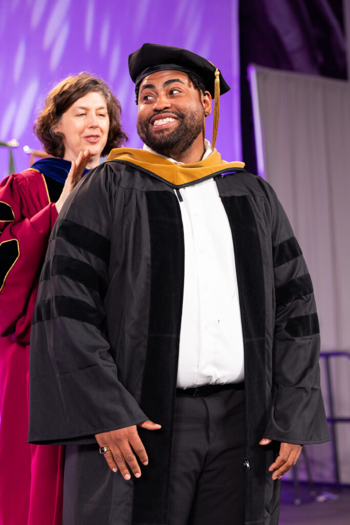 Dante Williams participates in a doctoral hooding ceremony during the Morrison Family College of Health; Opus College of Business Graduate Commencement Ceremony in the Field House in St. Paul on May 26, 2024.