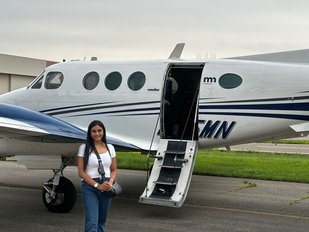 Dimpi Patel poses in front of a Minnesota Department of Transportation plane.