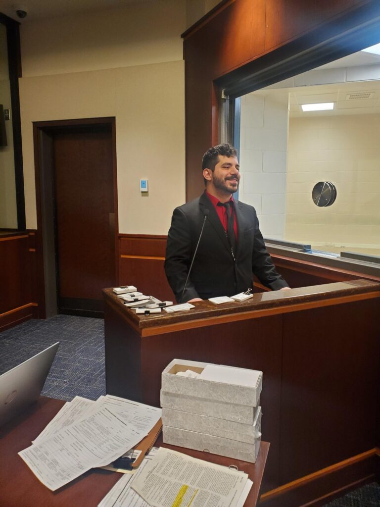 Chris Eliou standing behind a desk in a courthouse. 