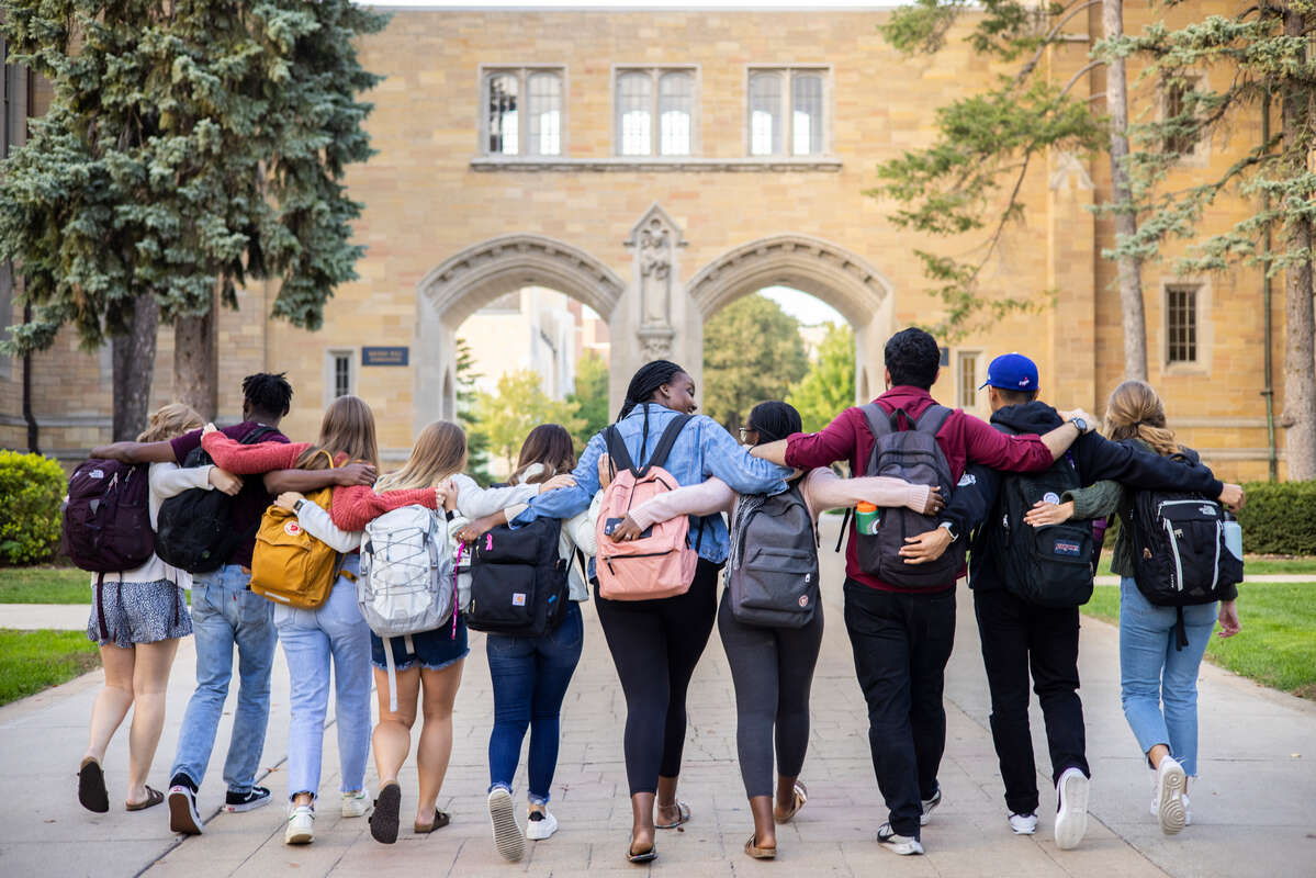 Students walk arm in arm by the Arches.