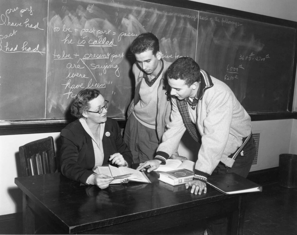 Woman teaching two students. Black and white.