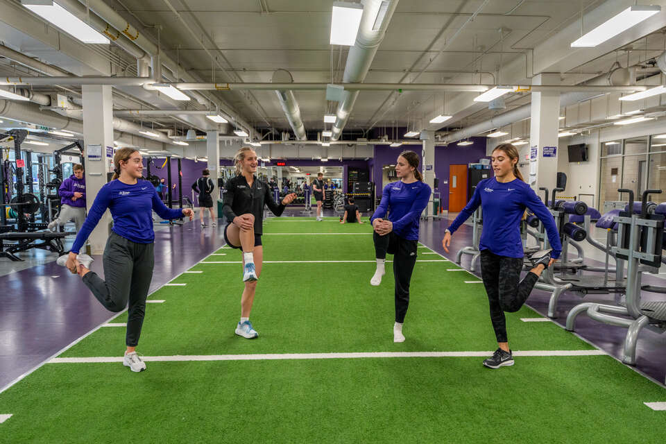 Members of the Women's Track and Field team stretch in the AARC workout space.