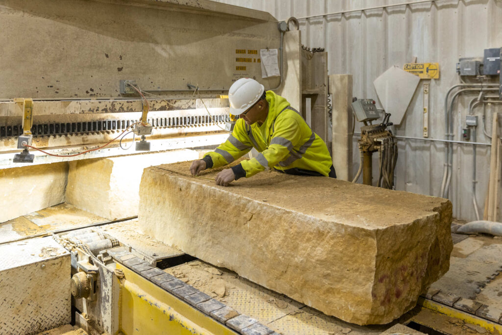 A plant worker at the Vetter Stone Company measures a large piece of Kasota limestone.