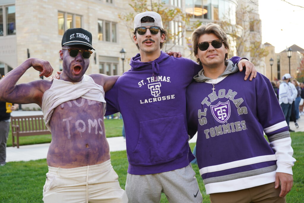 Three Tommie students decked in purple on the Purple Plaza