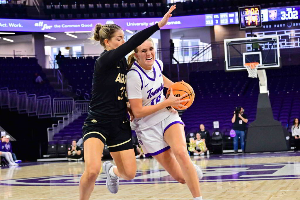 An offensive player drives the lane against a defender