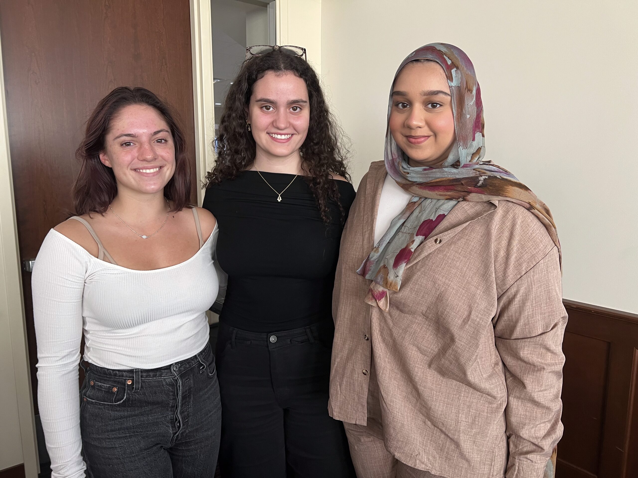 Three students stand and pose for a photo.