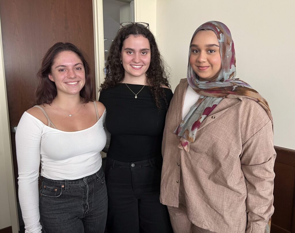 Three students stand and pose for a photo.