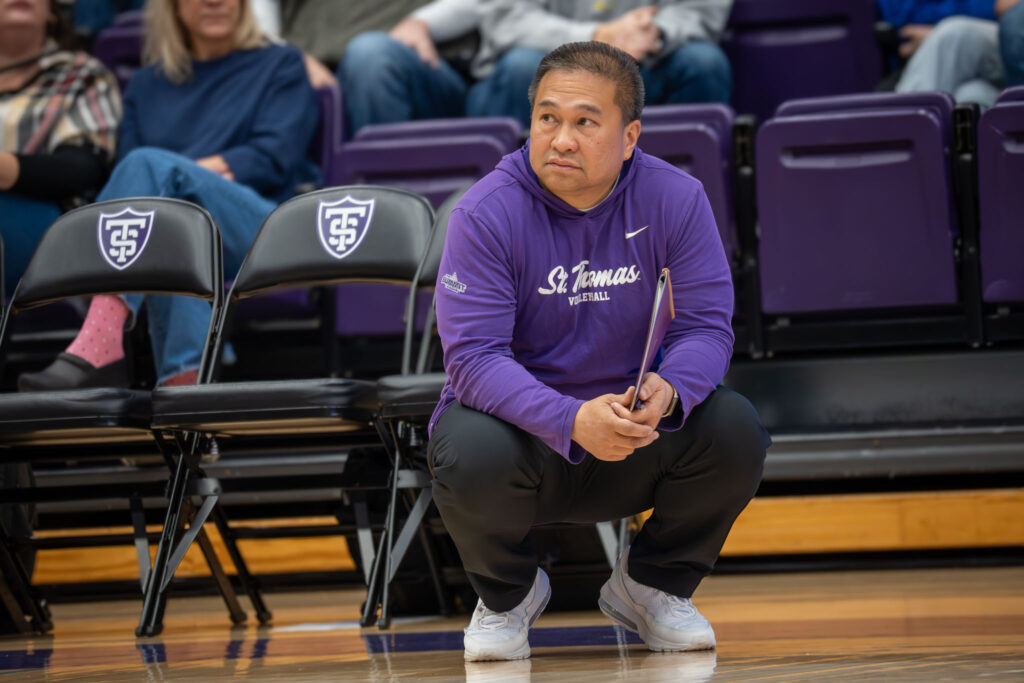 Coach Thanh Pham crouching on the sidelines