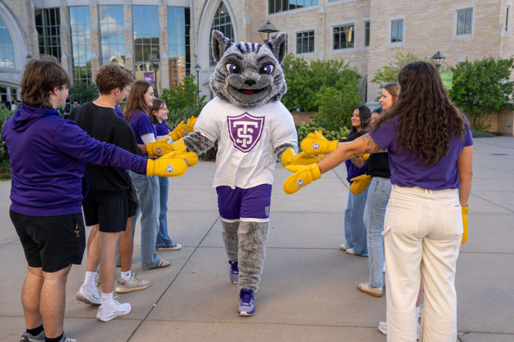 Tommie the mascot walking between students high five tunnel