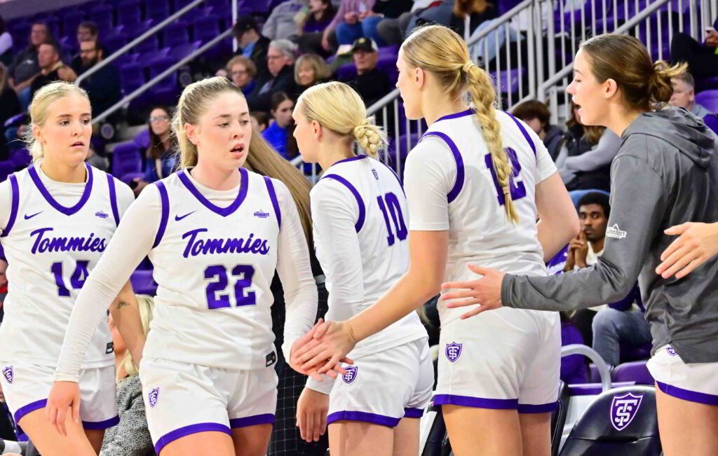 St. Thomas women's basketball players walk towards bench