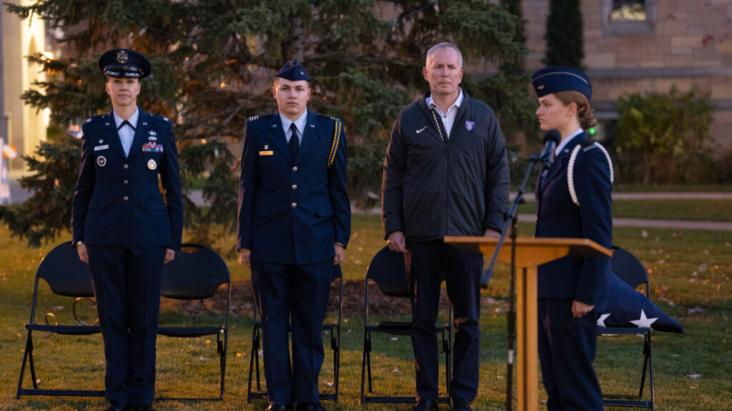 St. Thomas President Rob Vischer standing at attention with Members of Air Force ROTC Detachment 410 participating in the closing ceremony of a 24 hour vigil honoring military service members missing in action or prisoners of war on the lower quad in St. Paul. 