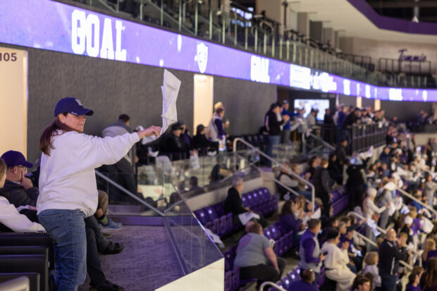 A spectator waving a towel inside a hockey arena.