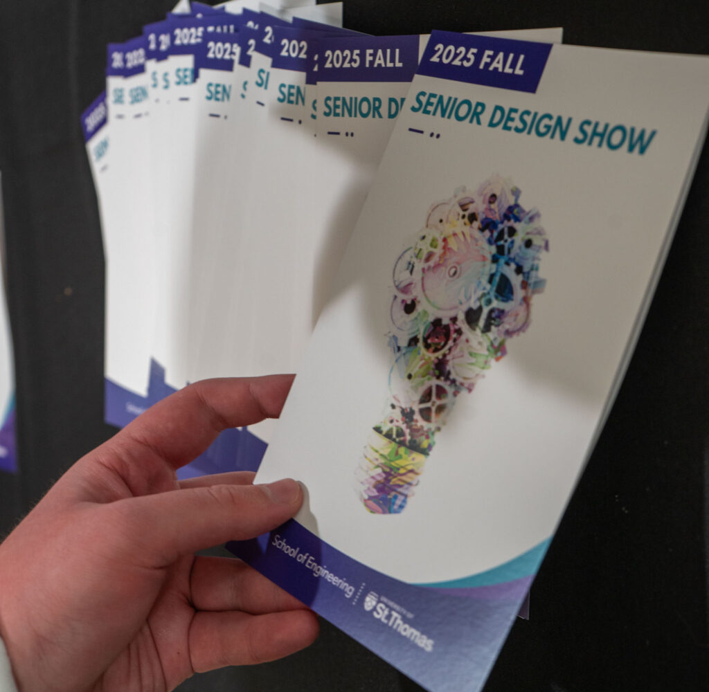 A student's hand picking up a brochure.