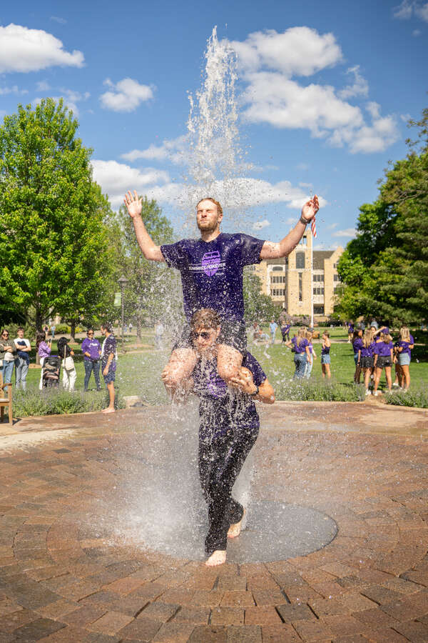 Students walk through the fountain on Monahan Plaza during March out of the Arches on May 23, 2025, in St. Paul.