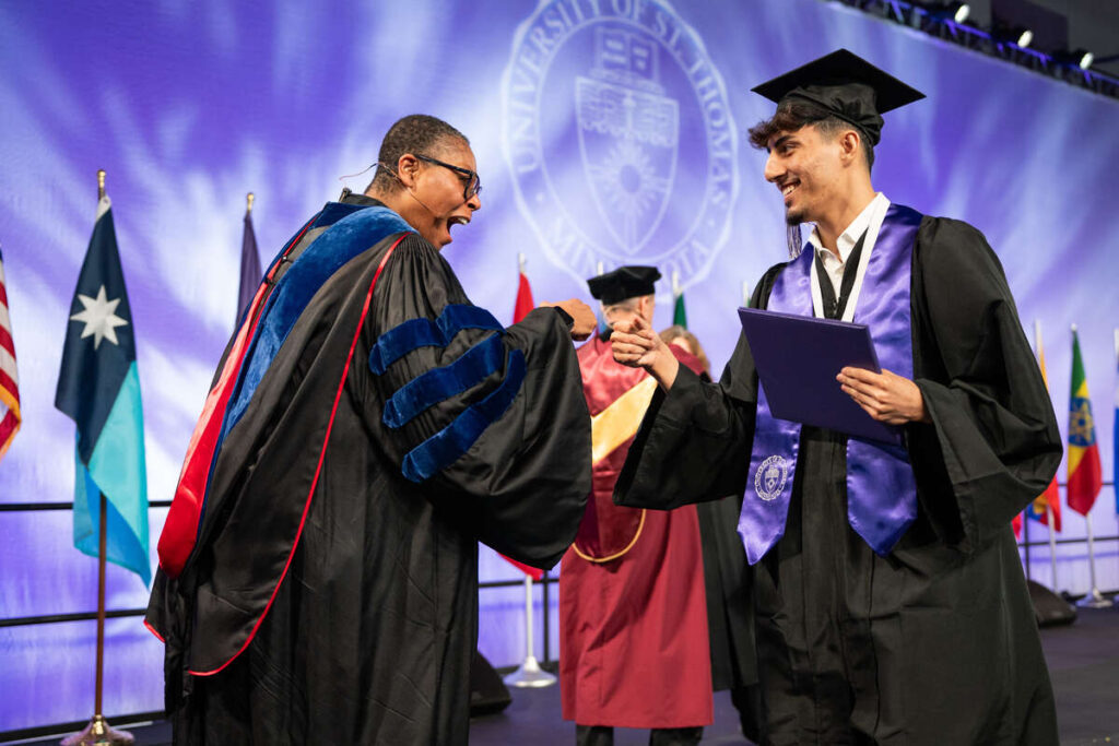 Dean Buffy Smith greets a student at the Undergraduate Ceremony for Dougherty Family College on May 25, 2025, in St. Paul.