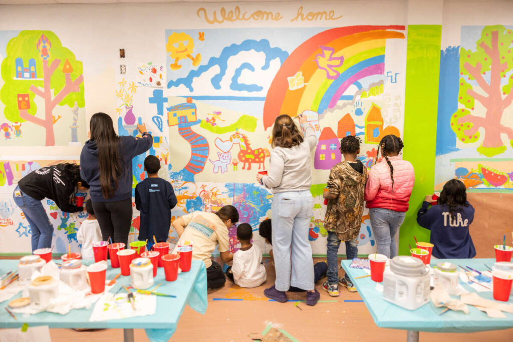 Professor Mike Klein, his students, and the kids and their families paint the mural at the Ramsey County Catholic Charities Family Service Center on November 08, 2025 in Maplewood.