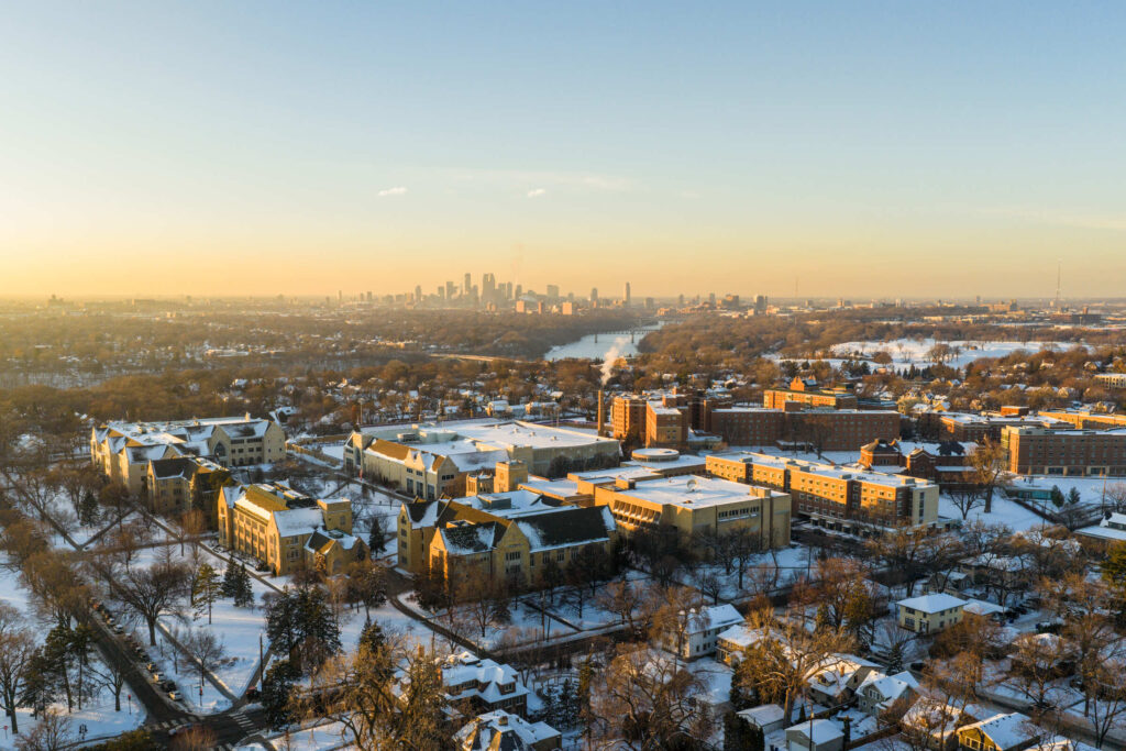 Aerial drone photos of campus with fresh snow taken on December 15, 2025, in St. Paul. The Minneapolis skyline is visible in the distance.