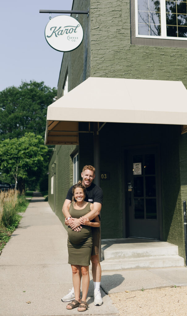 Megan and Nathan Whipples posing while hugging outside of green building