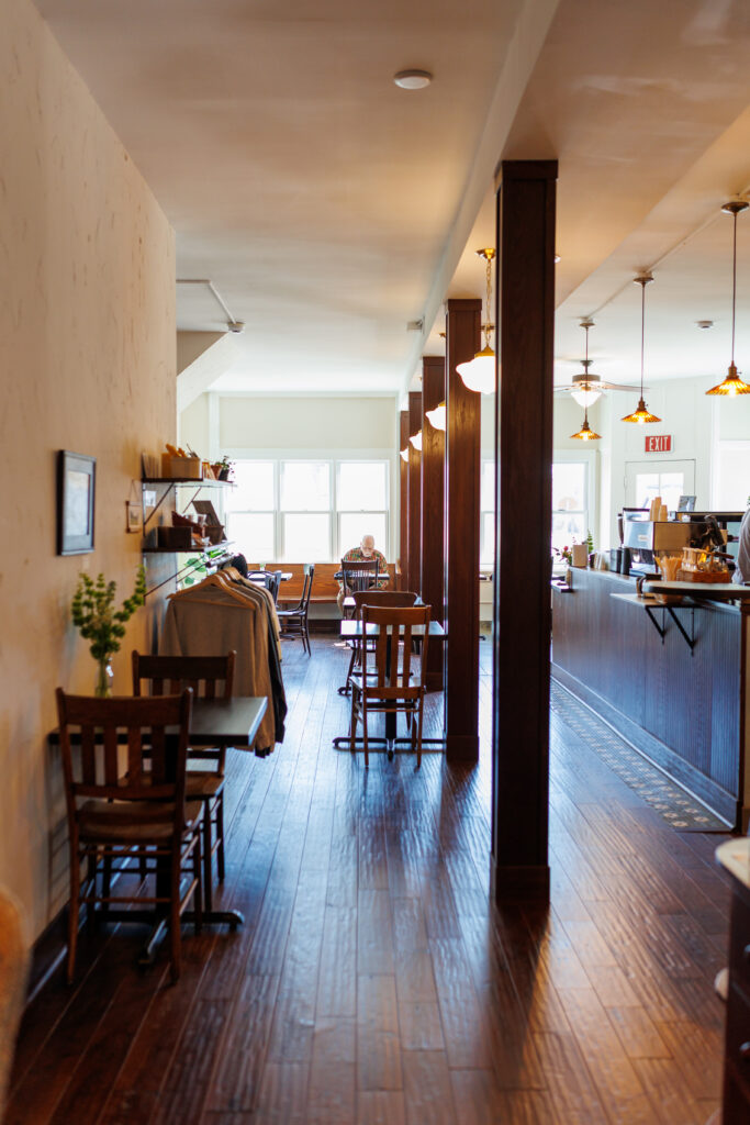 Inside picture of coffee shop with wooden furniture and bright light from windows