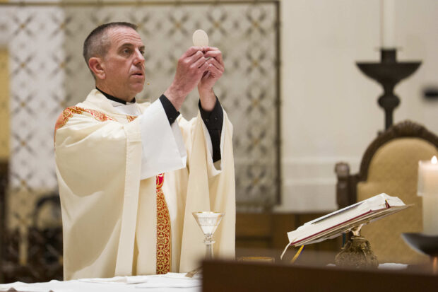 Father Chris Collins holds eucharist