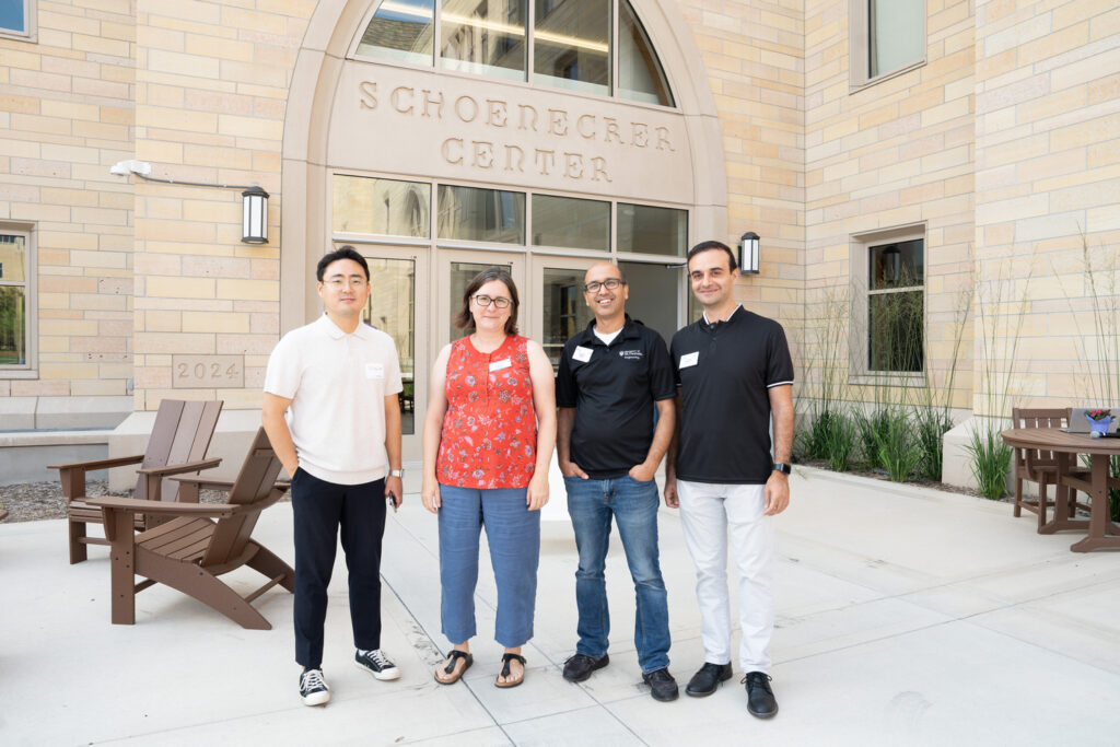 Four people stand in front of a building for a photo.