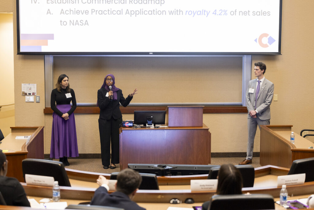 Three students talk in front of judges.