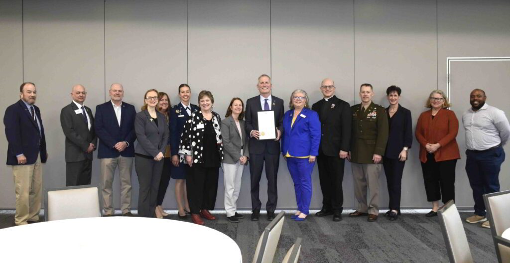 St. Thomas President Rob Vischer holds a proclamation in a group photo.