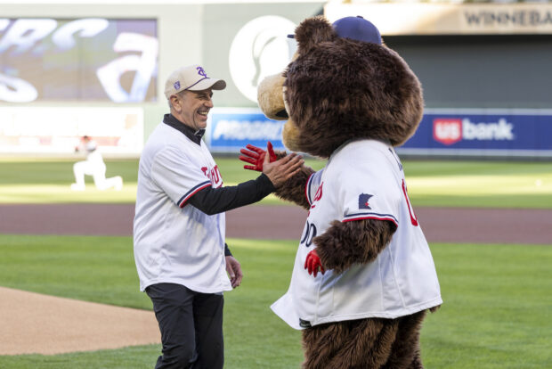 Father Chris Collins celebrates with Minnesota Twins mascot T.C. Bear on the field.