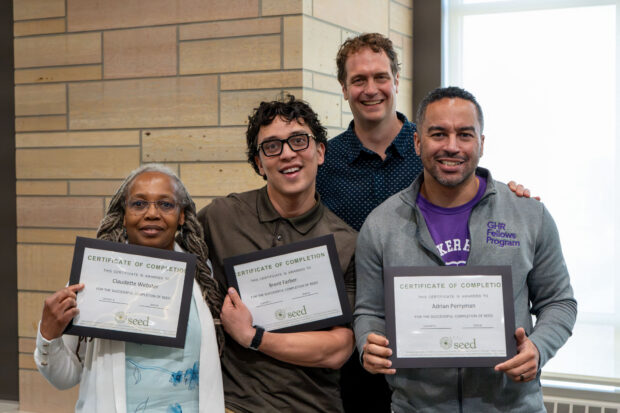 Four people take a group photo and three are holding certificates.