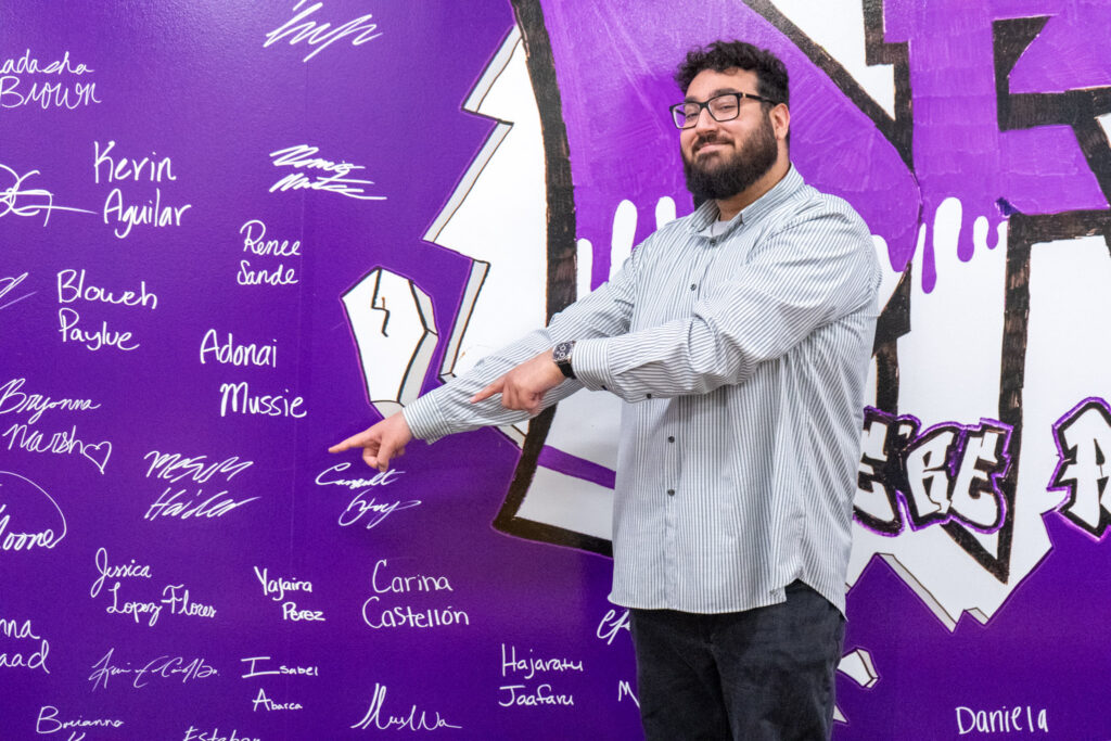 Mesum Haider points at his name on the wall.