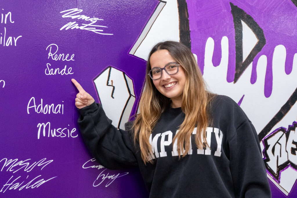 Renee Sande points at her name on the wall.