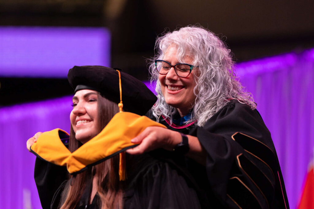 A graduate is hooded during the Morrison Family College of Health, Opus College of Business Graduate Commencement Ceremony. Liam James Doyle/University of St. Thomas