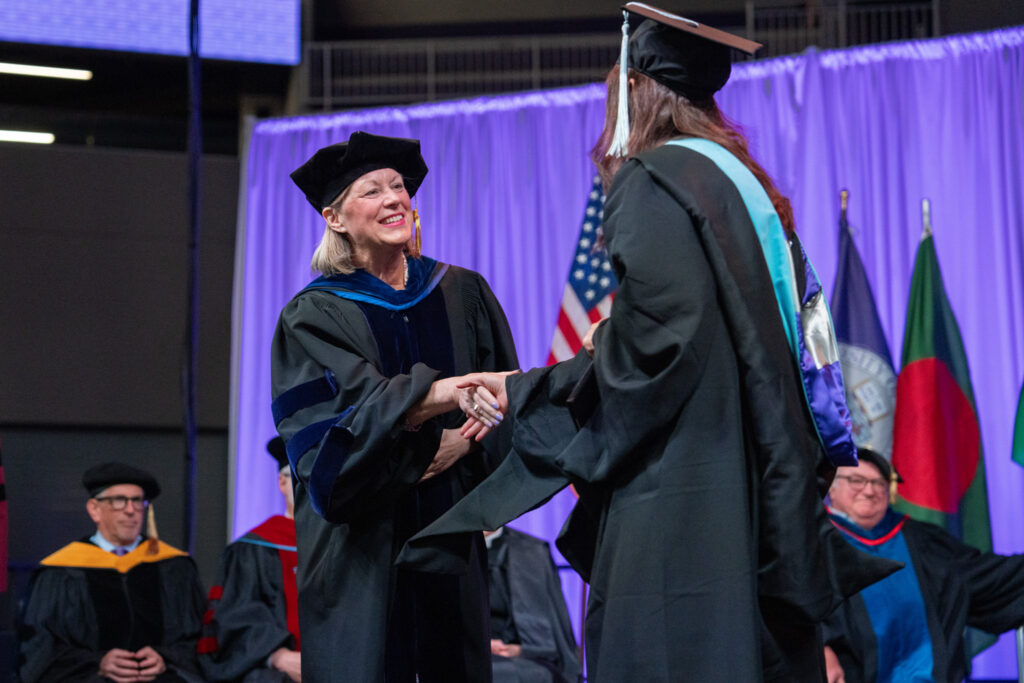 Dr. Amy F. Smith shakes hands with a student during a commencement ceremony.