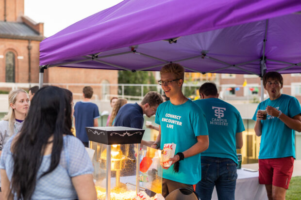 Students gather around a tent to get popcorn at a Campus Ministry event.