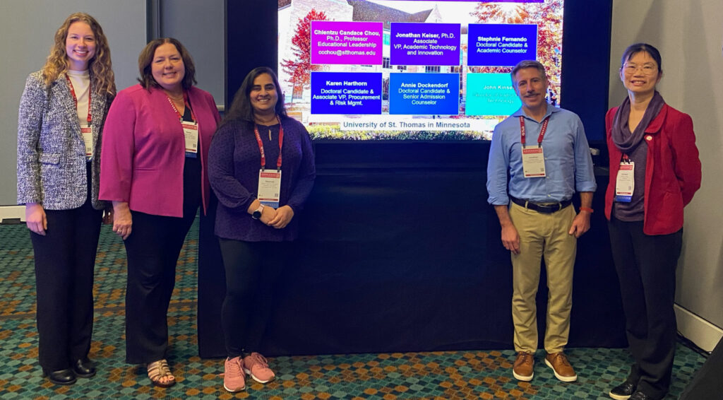 Five members of the Educause group line up for a photo in front of a projector.