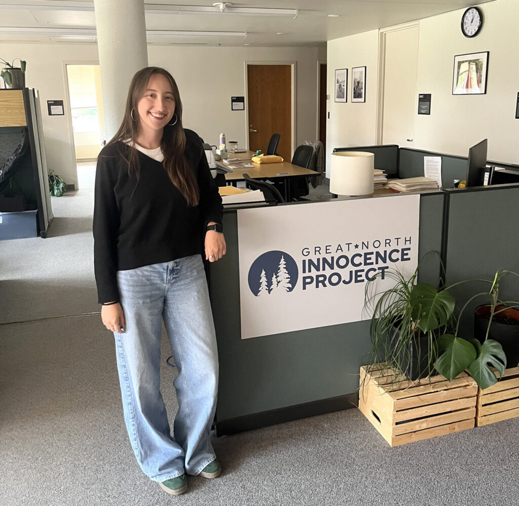Kayla Abrams-Mahoney poses for a photo inside by a cubicle in an office setting.