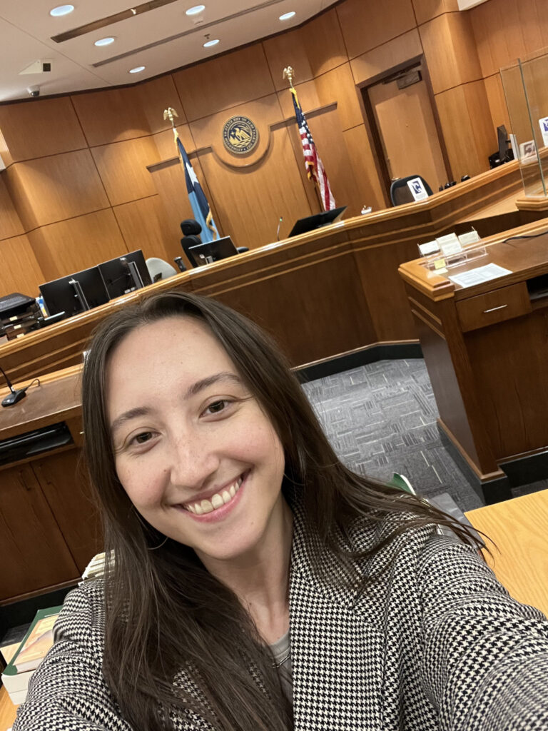 Kayla Abrams-Mahoney smiles for a selfie in an open court room.