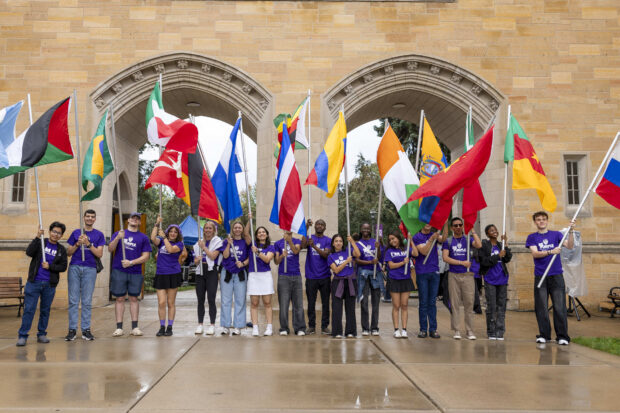 Students hold home country flags at The Arches.