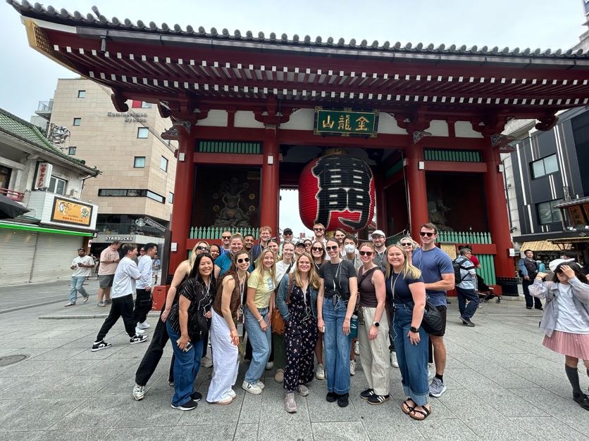A group of students outside pose for a photo in Asia.