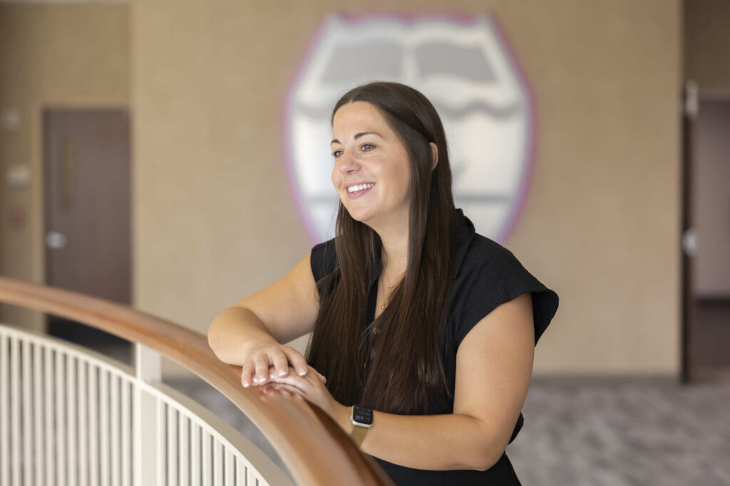 Samantha Harris smiling for a portrait against the rails on the second floor of Schulze Hall.