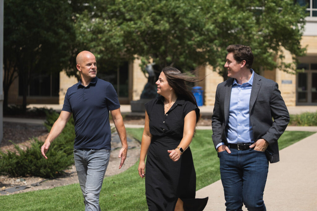 Ryan Backer, Samantha Harris and Sam Larson walking together outside on the Minneapolis campus.