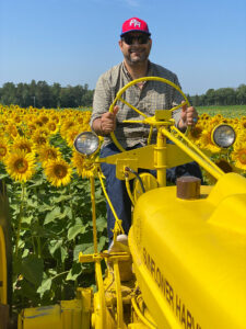 Mahmoud Elgendy operating a tractor in a field of dandelions.