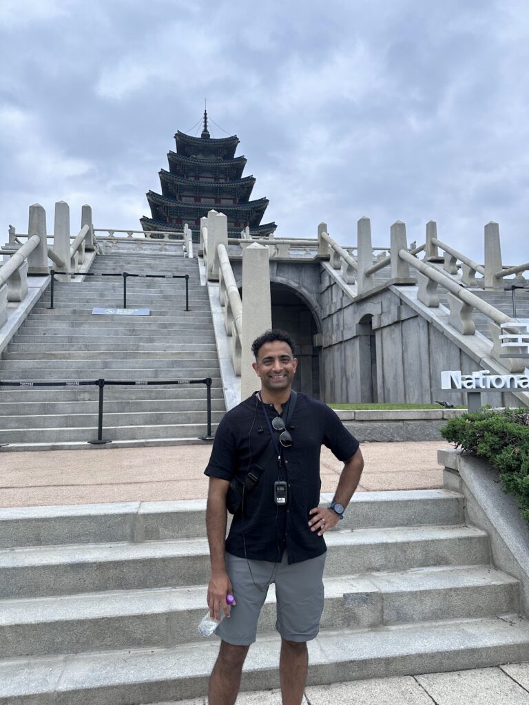 A student poses for a photo outsides by the steps leading to a building in Asia during an international travel trip.
