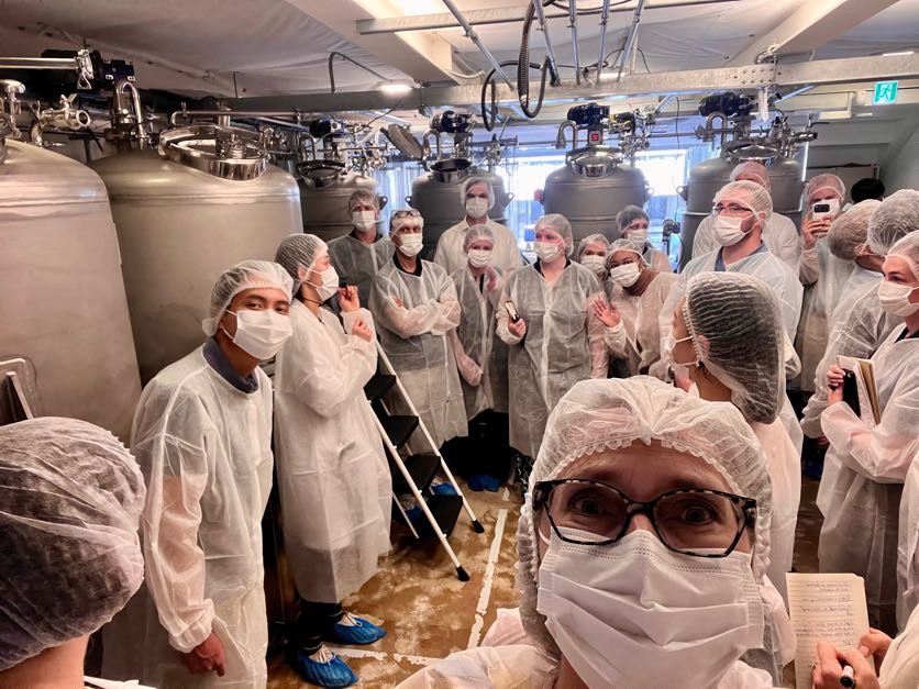 A selfie taken with a group of students wearing masks and hair caps during a site visit at a brewery.