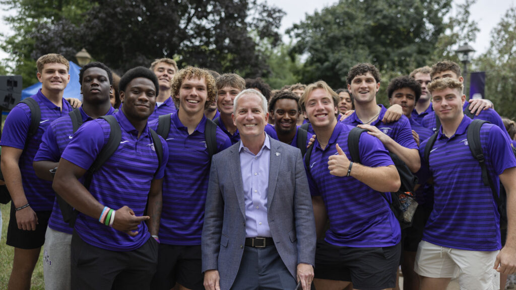 President Rob Vischer and a group of students behind him smile for a photo.