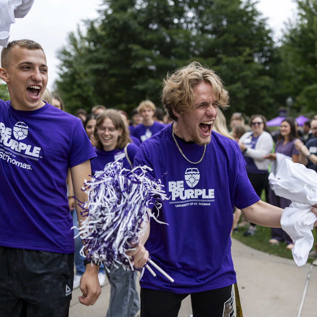 A student holding a pom pom shouts in excitement.