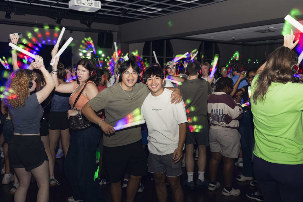 Students smile for a photo during a headphone disco event.
