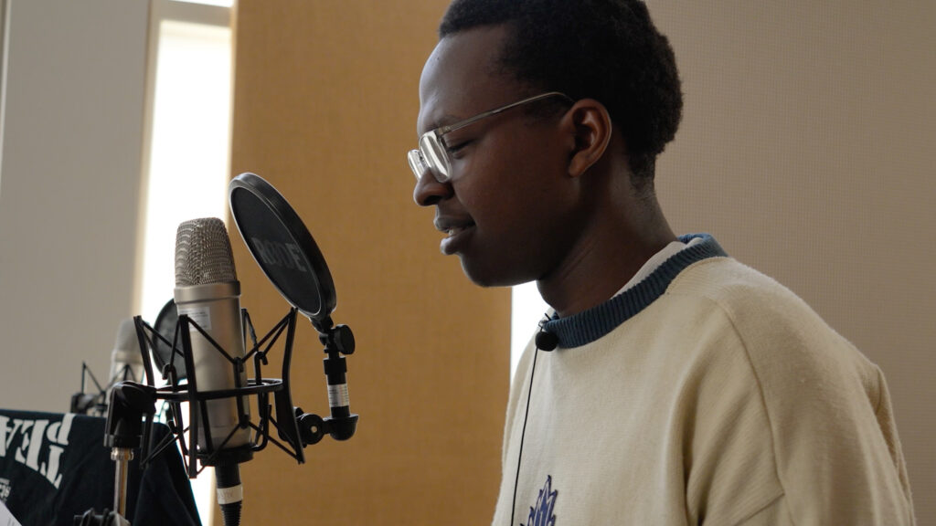 Student David Musherure speaks into a microphone.