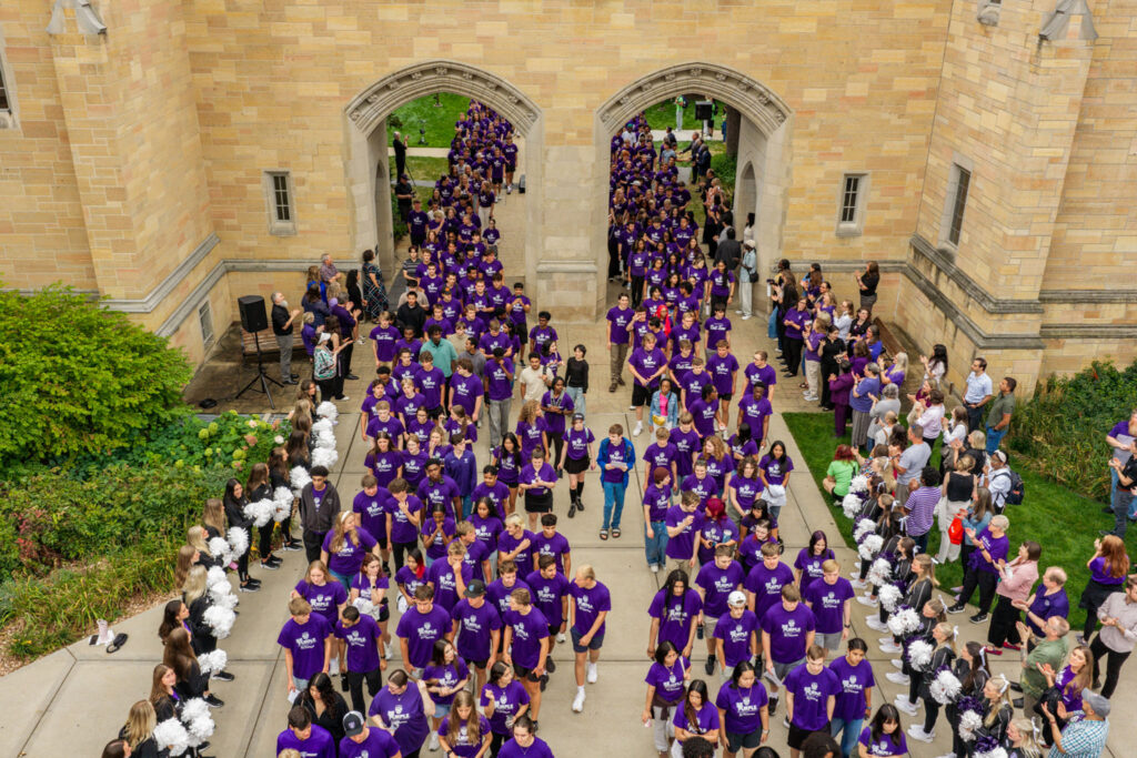 An overview shot from a drone showing a sea of students wearing purple t-shirts.